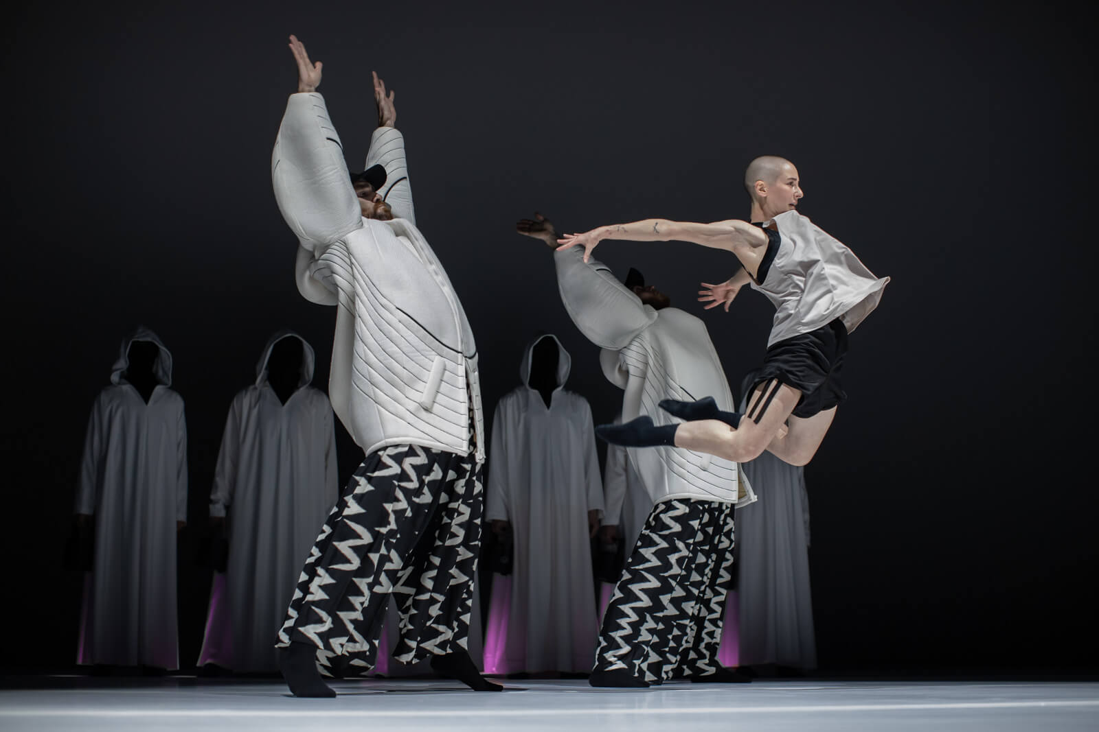 A dancer leaps into the air, arms and legs outstretched behind them.